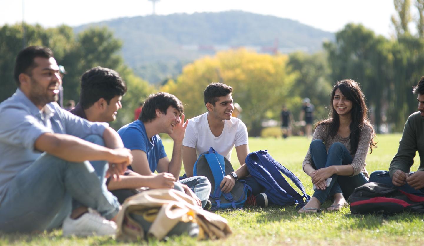 Group of students chatting on grass oval