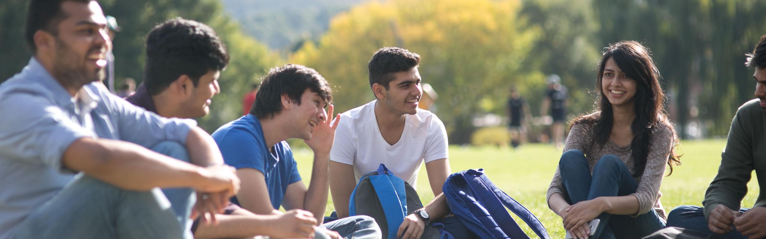 Group of students chatting on grass oval